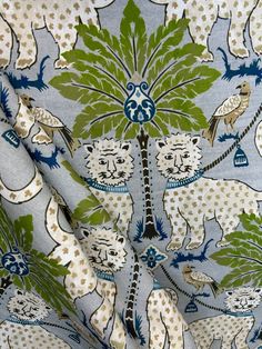 a blue and white fabric with lions on it's side, surrounded by green leaves