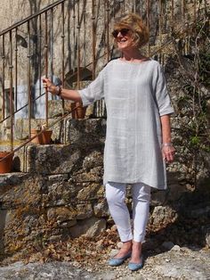 a woman standing on top of a rock covered hillside next to a stone wall and stairs