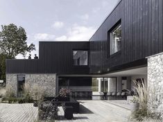 the house is made out of black wood and has an outdoor deck with seating area