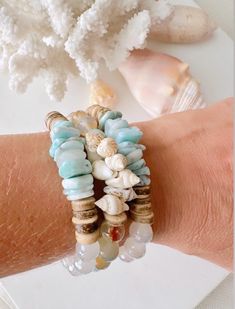 A customer favorite!  Great bracelet for all seasons!  Add something fresh and new to your accessory collection that can be stacked, worn alone or mixed together with your favorite pieces. These uniquely ornate beachy inspired neutral IzaTazi bracelets will definitely make your look stand out! This bracelet features:  1 Size 7" stretch style bracelet    Organic shaped Larimar chips  seashell beads  Coconut shell beads  white mystic agate or Sedona agate BRACELET CARE INSTRUCTIONS: *Keep jewelry Cheap Beach Stretch Bracelet With Round Beads, Ocean-inspired Beaded Bracelets For Beach, Ocean-inspired Beaded Bracelet For Beach Season, Handmade Blue Wrap Bracelet For Beach, Bohemian Stackable Stretch Bracelet For Beach, Handmade Bohemian Stretch Bracelet For Beach Season, Bohemian Stackable Wrap Bracelet For Beach, Beachy Friendship Bracelets For Beach Season, Bohemian Hand-strung Stretch Bracelet For The Beach