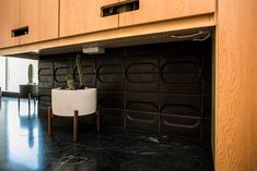 a room with black and white marble flooring, wooden cabinets and a potted cactus