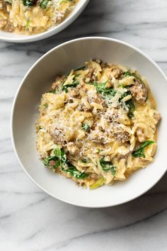 two white bowls filled with pasta and meat