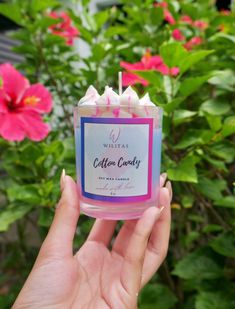 a hand holding a pink candle in front of some red and white flowers with the words cottage country written on it