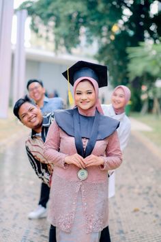 two women in graduation gowns standing next to another woman wearing a cap and gown