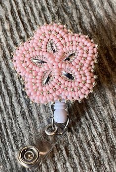 a pink beaded brooch with a white button attached to it on a wooden surface