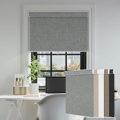 an office with grey shades and white desks in front of a window that has plants on it