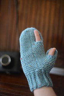 a person's hand wearing a blue knitted mitt next to a camera