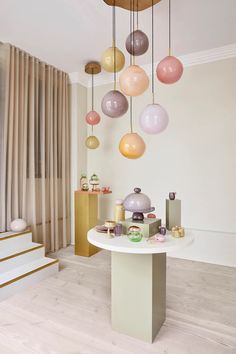 a white table topped with lots of different colored balls hanging from it's ceiling