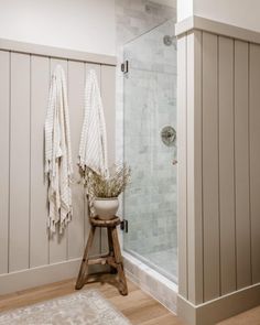 a bathroom with a stand up shower next to a white rug and wooden flooring