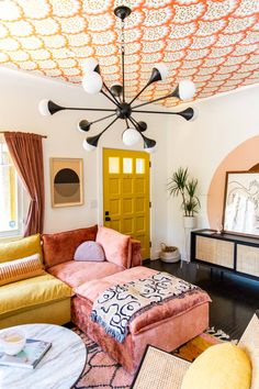 a living room filled with furniture and a ceiling painted in orange, white, and pink