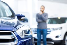 a man talking on the phone in front of some cars