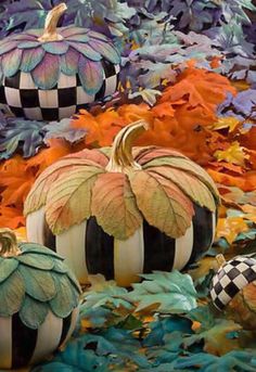 three pumpkins sitting on top of leaves in front of a pile of autumn leaves