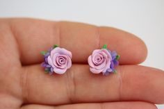 two tiny pink roses are sitting on someone's finger and they look like they were made out of polymer