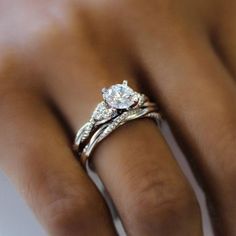 a woman's hand with a diamond ring on her left hand and an engagement band