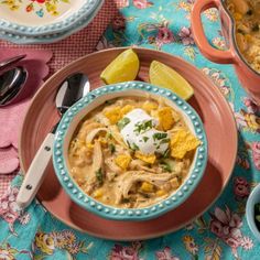 a bowl of soup with sour cream and tortilla chips on the side next to it