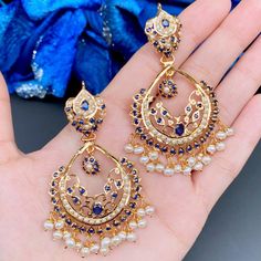 Featuring a pair of handcrafted gold plated, jadau chandbali earrings. Made in 925 sterling silver and embellished with precious pearls and blue sapphire look alike navy blue stones. Blue Fusion Jewelry With Intricate Design, Blue Kundan Chandbalis For Celebration, Blue Temple Jewelry Jhumkas For Celebration, Blue Gold-plated Earrings For Wedding, Blue Temple Jewelry Earrings For Festive Occasions, Traditional Blue Earrings With Intricate Design, Blue Temple Jewelry With Intricate Design, Temple Style Blue Jhumkas For Celebration, Blue Temple Jewelry Earrings With Latkans