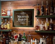 a bar with liquor bottles and glasses on the shelves, along with a framed sign that says neon bar