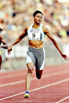 a woman running on a track with her arms outstretched