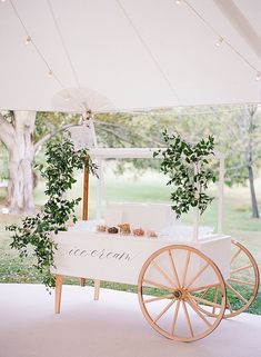 a white cart with greenery on it under a tent