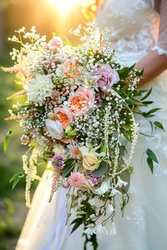 a bridal holding a bouquet of flowers and greenery with the sun behind it