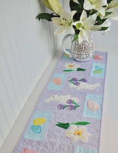 a vase filled with white flowers sitting on top of a table next to a wall