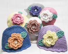 several crocheted hats with flowers on them