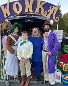 three adults and two children standing in front of a sign that says wonka on it