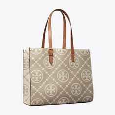 T Monogram is a classic pattern inspired by Pennsylvania Dutch quilting. The collection speaks to the timelessness of great style.  The tote is crafted in contrast embossed leather with an adjustable shoulder strap. Each side of the tote features an inverse color combination, creating two looks in one. Lined in soft microsuede with an interior laptop sleeve, every detail is considered, with special attention to function and versatility.   Crafted in partnership with a Leather Working Group-certi Classic Tan Coated Canvas Shoulder Bag, Classic Tan Monogram Canvas Shoulder Bag, Classic Tan Bags In Signature Coated Canvas, Everyday Leather Shoulder Bag With Monogram Print, Leather Shoulder Bag With Monogram Print For Everyday, Beige Monogram Print Bag For Everyday Use, Classic Top Handle Bag With Monogram Print, Classic Monogram Print Shopping Bags, Elegant Tan Shoulder Bag In Signature Coated Canvas