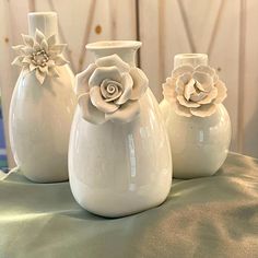 three white vases sitting on top of a table