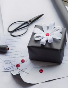 a black gift box sitting on top of paper next to scissors