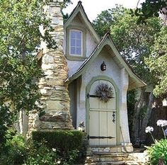 a small house with a door and window on the outside, surrounded by greenery