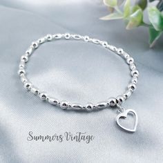 This simple and dainty sterling silver bracelet featuring a beautiful open-heart charm looks stunning worn alone or stacked alongside other bracelets for a Bohemian feel   The eclectic mix of beautiful beads are strung on high quality, strong, professional jewellers' elastic meaning there are no fiddly clasps to deal with, the bracelet can simply be rolled over the hand and onto the wrist The bracelet is elegantly presented in a beautiful jewellery pouch, complete with aftercare instructions and Elegant Silver Beaded Bracelets With Heart Charm, Elegant Silver Beaded Bracelet With Heart Charm, Elegant Sterling Silver Beaded Bracelet With Heart Charm, Dainty Heart Charm Bracelet With Round Beads, Elegant Metal Beaded Bracelet With Heart Charm, Dainty Jewelry With Heart Charm And Round Beads, Dainty Sterling Silver Charm Bracelet With Heart Charm, Dainty Beaded Bracelet With Heart Charm, Elegant Silver Charm Bracelet With Heart Beads