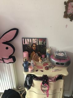 a vanity with various items on it and a bunny stuffed animal hanging from the wall