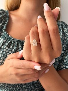 a woman wearing a ring with a flower on it's middle finger and holding her hands together