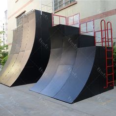 three skateboard ramps in front of a building with red scaffolding around them