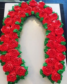 a cake decorated with red roses and green leaves