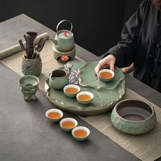 a person sitting at a table with tea cups and saucers