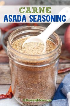 a jar filled with seasoning sitting on top of a table next to an apple