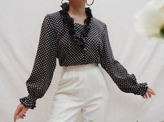 "Vintage black and white polka dot long sleeves blouse with ruffled detail on collar, front and cuffs, buttons up at the front and cuffs. The shape and detailing of this piece are so beautiful! Clean and comfortable to wear. Great vintage condition, no stains or tears. Material 100% Polyester Measurements (approximately) : Size on label : 9 Best fit : XS/S (see measurements) Bust : 36\" Shoulder : 15\" Waist : 29\" Length : 20.5\" Sleeve length from shoulder: 22.5\" For reference, model is 5'3\" Polka Dot Long Sleeve Blouse For Work, Polka Dot Ruffled Blouse For Work, Polka Dot Ruffle Blouse For Work, Chic Polka Dot Blouse With Ruffles, Vintage Polka Dot Blouse For Work, Japanese Blouse, Vintage Polka Dot Blouse For Workwear, Retro Black Button-up Blouse, Retro Fitted Polka Dot Blouse