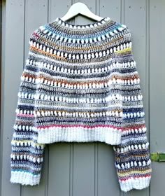 a knitted sweater hanging on the side of a door with a hanger in front of it