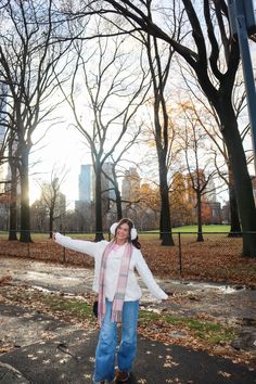 a woman standing in the middle of a park with her arms spread out and headphones on