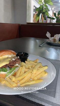 a hamburger and french fries on a white plate at a table in a restaurant,