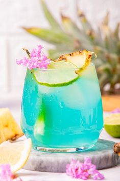 a blue and green drink sitting on top of a table next to sliced pineapples