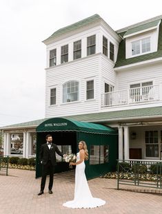 a bride and groom standing in front of a large white building with a green awning