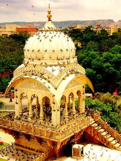 an aerial view of a building in the middle of trees and buildings with birds flying around it