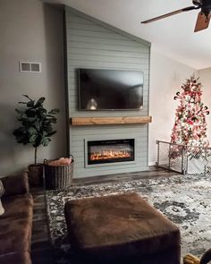 a living room with a christmas tree in the corner and a flat screen tv above it