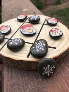 some rocks are arranged on top of a wooden board with snowflakes and santa's hats