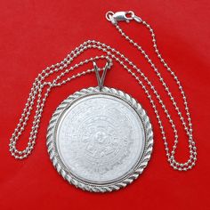 "A gorgeous sterling silver necklace, set with an authentic Mexico 1 oz Silver Round BU Uncirculated Coin - Aztec Calendar. Obverse: Depicts the famous Aztec Calendar stone. The design is in a circular shape resembling a sun, with rays emanating outward. In the center is the face of the Aztec solar deity, Tonatiuh, which gives the monolith its alternate name the Sun Stone. Reverse: depicts the striking left portrait of Cuauhtemoc, the last Aztec Emperor of Tenochtitlan. The name Cuauhtemoc means Silver Etched Sterling Silver Necklace, Etched Sterling Silver Necklaces, Etched Sterling Silver Round Necklace, Etched Sterling Silver Round Pendant Jewelry, Silver Etched Round Pendant Jewelry, Etched Sterling Silver White Gold Necklace, Sterling Silver Etched Amulet Necklace, Sterling Silver Etched Coin Jewelry, Etched Coin-shaped Sterling Silver Jewelry