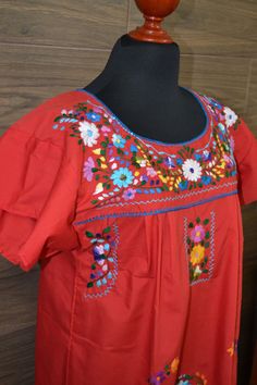 "This lovely red was handmade in Mexico. The beautiful colorful flowers were embroidered by hand, so each one is unique. You will love wearing this comfortable cotton dress with short sleeves. It is perfect for a hot summer day. This dress comes just above or below the knee, depending on how tall you are. It has a square neckline and cute little puffy sleeves. The measurements on this dress are 21\" wide x 44\" long. It has a 9\" opening for the neck and 10\" sleeve openings. Size Large About Ou Red Folk Embroidered Dress With Floral Design, Traditional Red Embroidered Spring Dress, Red Folk Style Dress With Floral Embroidery, Traditional Red Embroidered Dress For Spring, Traditional Cotton Embroidered Fiesta Dress, Red Bohemian Embroidered Dress With Floral Details, Traditional Embroidered Cotton Dress For Fiesta, Red Bohemian Embroidered Dress With Intricate Embroidery, Traditional Cotton Embroidered Dress For Fiesta