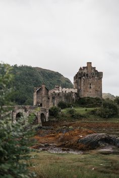 an old castle sitting on top of a lush green hillside